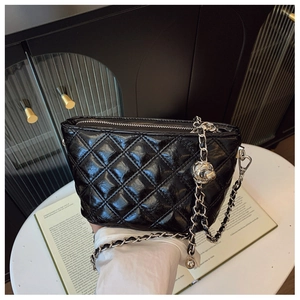 Detail of black quilted leather shoulder bag featuring silver chain and metal ball charm