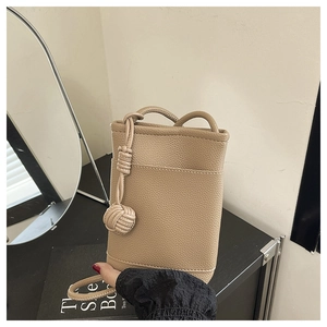 Detail of khaki pebbled leather mini crossbody bag with a unique woven rope knot charm