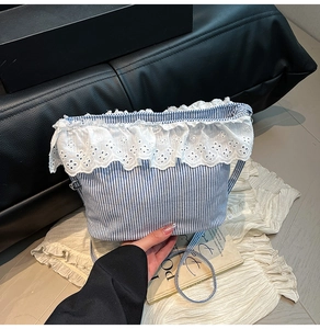 Detail of blue striped bucket bag featuring intricate white lace trim and slim strap