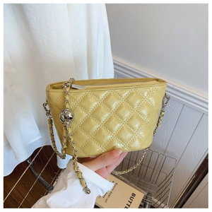 Detailed close-up of yellow glossy quilted leather bag with silver metal chain strap