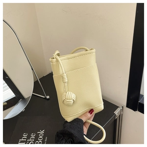 Detail of light yellow lychee pattern mobile phone bag with a woven knot charm
