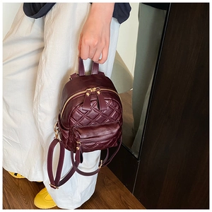 Detail of burgundy quilted leather mini backpack with golden zipper and front pocket