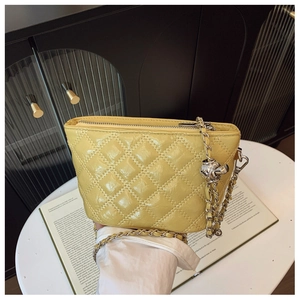 Detail of glossy yellow quilted chain bag with silver ball charm and metallic finish