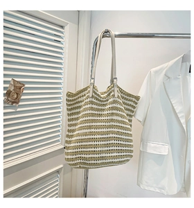 Detail of striped woven tote bag with cream leather strap and metal buckle adjustment