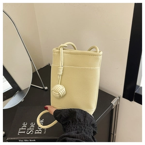 Close-up of a mini cream yellow leather crossbody phone bag with decorative woven ball knot