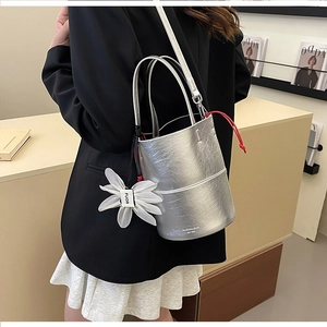 Detail of silver metallic pleated bucket bag with flower charm and red drawstring cord