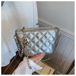Detail of silver quilted chain bag with metallic finish and woven shoulder strap