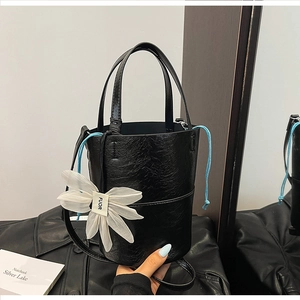 Detail of black oiled leather bucket bag with daisy charm and blue drawstring accent