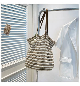 Detail of striped woven tote bag with adjustable leather straps and tulip charm