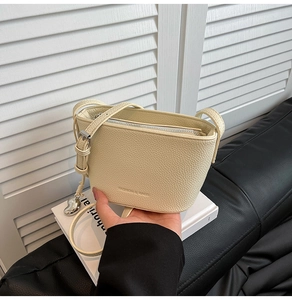 Nahaufnahme der beigen Beuteltasche aus Leder mit Herzanhänger und Fashion-Schriftzug
