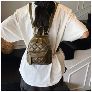 Mini olive green quilted backpack with golden hardware shown on a person's back