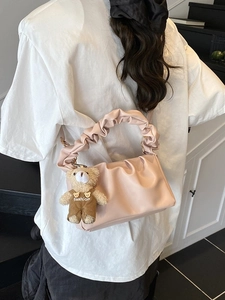 Pink ruched shoulder bag with a plush bear charm for a stylish casual look