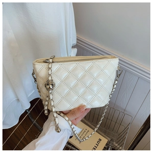 Close-up of cream quilted chain bag with glossy finish and gold metal ball detail