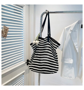 Detail of black and white striped knit tote bag with elegant black leather shoulder straps