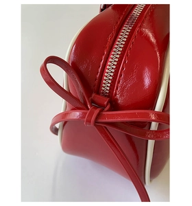 Close-up of red patent leather baguette bag featuring a bow detail and silver zipper