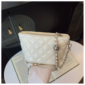 Detail of white quilted crossbody bag with silver chain strap on a designer magazine