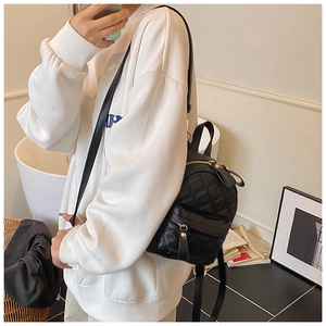 Lifestyle view of a mini black quilted backpack with golden zippers and slim straps
