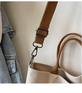 Detail of durable grey metal hook and brown woven strap on beige canvas tote bag