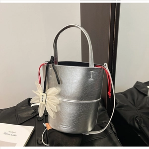 Silver metallic bucket bag with a red drawstring liner and white floral charm detail