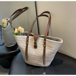 Close-up of woven straw tote bag with brown leather handles and interior flower decor