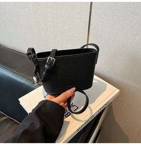 Detail der schwarzen Beuteltasche aus genarbtem Leder mit silberner Schnalle und Logo