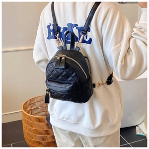 Close-up of black quilted backpack with golden zippers shown on model's back