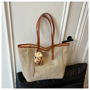 Détail du sac cabas en paille tressée avec lanières en cuir marron et breloque ours
