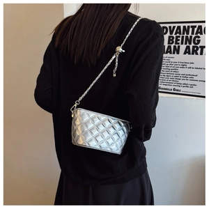 Detail of silver quilted chain bag featuring adjustable metal ball and tassel on the strap