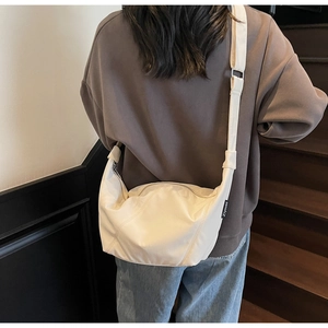 Detailansicht einer beigen Nylon-Umhängetasche in Halbmondform mit verstellbarem Gurt