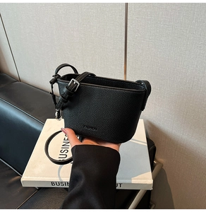 Detail der schwarzen Mini-Beuteltasche mit strukturierter Narbung und FASHION-Prägung
