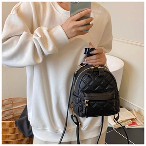 Detailed view of black quilted mini backpack with golden zipper and leather texture