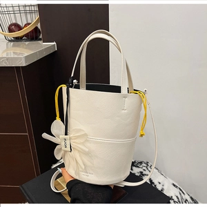 Detailed macro view of litchi texture white bucket bag with yellow drawstring lining