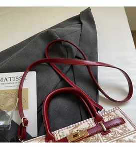 Detail of red leather bag with embroidery, adjustable shoulder strap and gold hardware