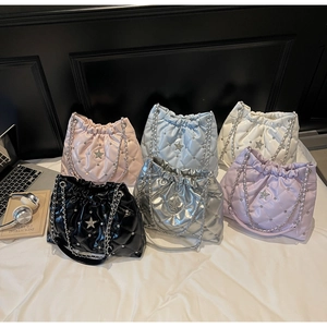 Flat lay of six colorful quilted bucket bags with silver rivets and star charms on a white bed