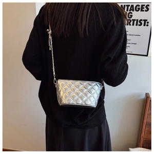 Detail of silver quilted crossbody bag with metal chain strap shown on model's back