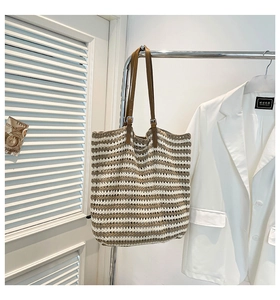 Detailed view of woven tote bag featuring brown stripes and adjustable leather strap