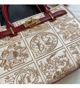 Detailed macro view of the intricate gold floral embroidery and metallic twist lock closure