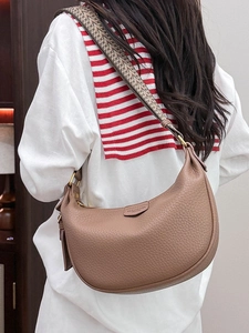 Brown litchi leather hobo bag with ethnic wide strap shown on model in a casual setting
