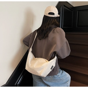 Detail der minimalistischen cremefarbenen Sichel-Tasche mit Reißverschluss und Nylontextur