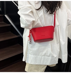 Detail der roten Mini-Beuteltasche aus genarbtem Leder mit FASHION-Prägung und Knoten-Anhänger