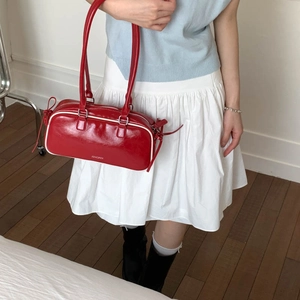 Detail of red wax leather Boston bag with white piping and silver metal zipper closure