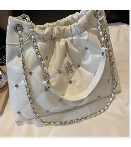 Detail of white quilted bucket bag with star pendant, drawstring, and metal chain strap