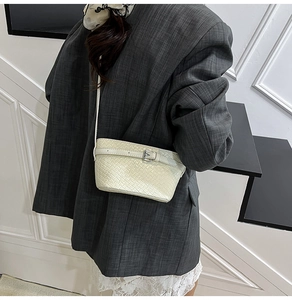 Dettaglio della trama intrecciata crema e fibbia metallica della borsa a tracolla alla moda