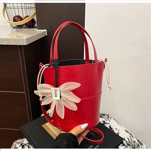 Close-up of a glossy red bucket bag featuring a large mesh flower with brand logo detail