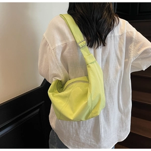 Nahaufnahme der neongrünen Dumpling-Tasche mit verstellbarem Gurt an einem Model