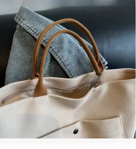 Detail of canvas tote bag with brown braided handles and secure metal zipper closure
