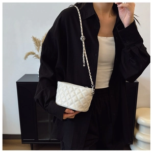 Detail of white quilted crossbody bag with silver chain and adjustable metal ball