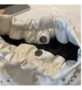 Close-up of white quilted bucket bag with silver magnetic clasp and rhinestone studs