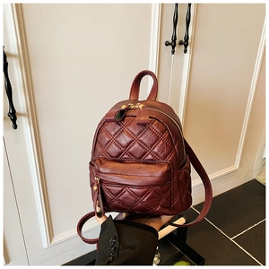 Detailed close-up of wine red quilted faux leather mini backpack with gold hardware