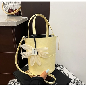 Detail of light yellow bucket bag with white flower charm and drawstring closure